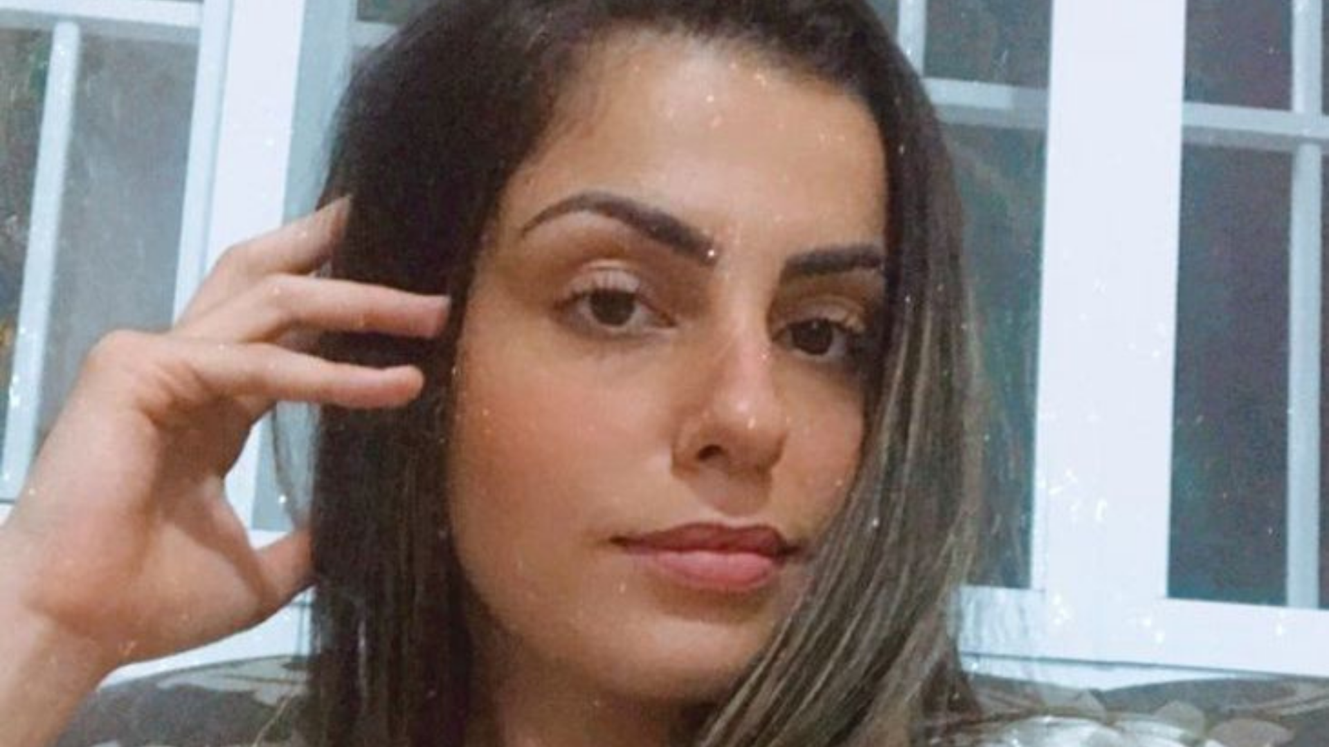 Bruna tem cabelos loiros, usa cabelo liso solto, pelo branca e olhar sério.