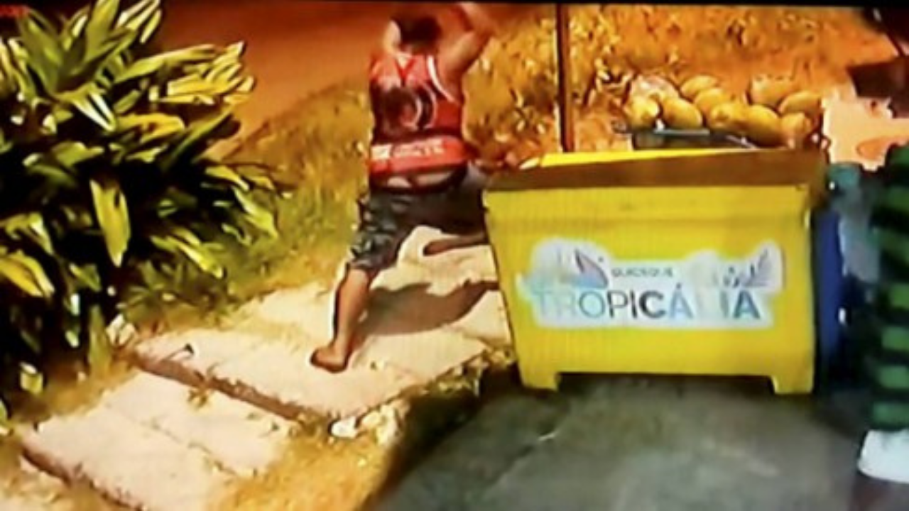 Foto de homem agredindo Moise ao lado de um freezer com o nome "Quiosque Tropicália"