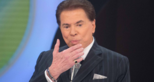 Juíza impõe derrota a Silvio Santos. Ele usa terno preto, anel no dedo mindinho, cabelo preto e pele branca.