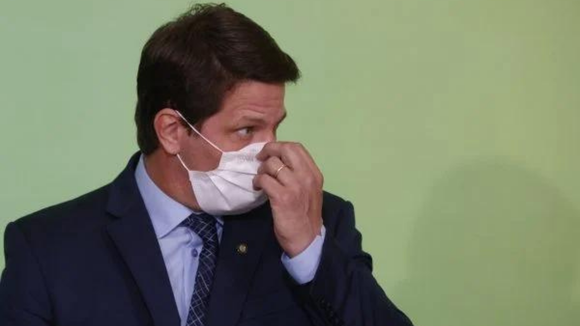 Caiu na rede: Mário Mamata. Ele usa máscara branca e terno preto, olha para a lateral e tem olhar preocupado.