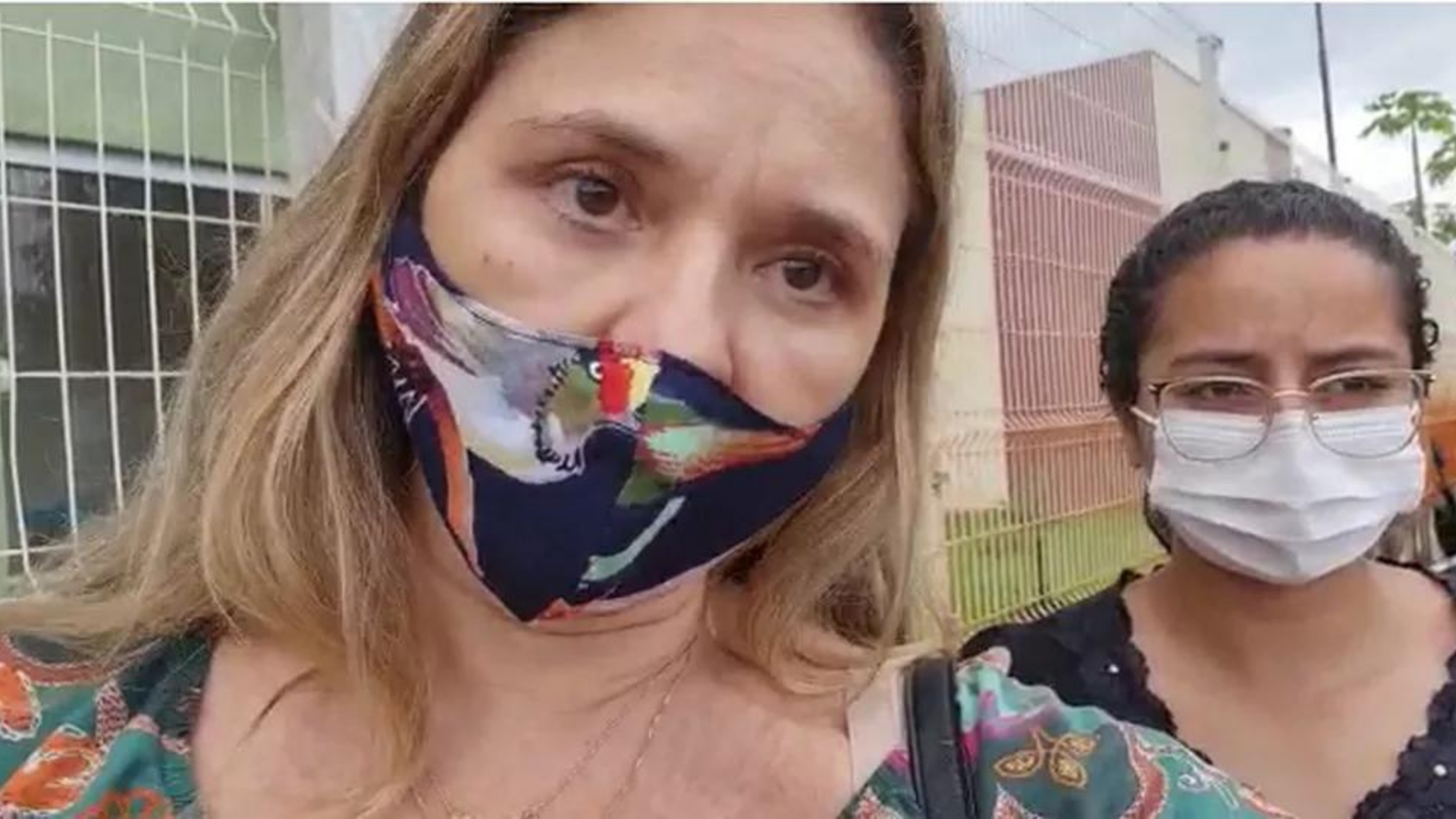 Petrobrás proíve não vacinados de fazer concurso. Na foto, uma mulher com cabelos loiros e máscara de pano faz um vídeo ao lado outra, com pelo negra, máscara cirúrgica, óculos de grau e cabelos cacheados presos.