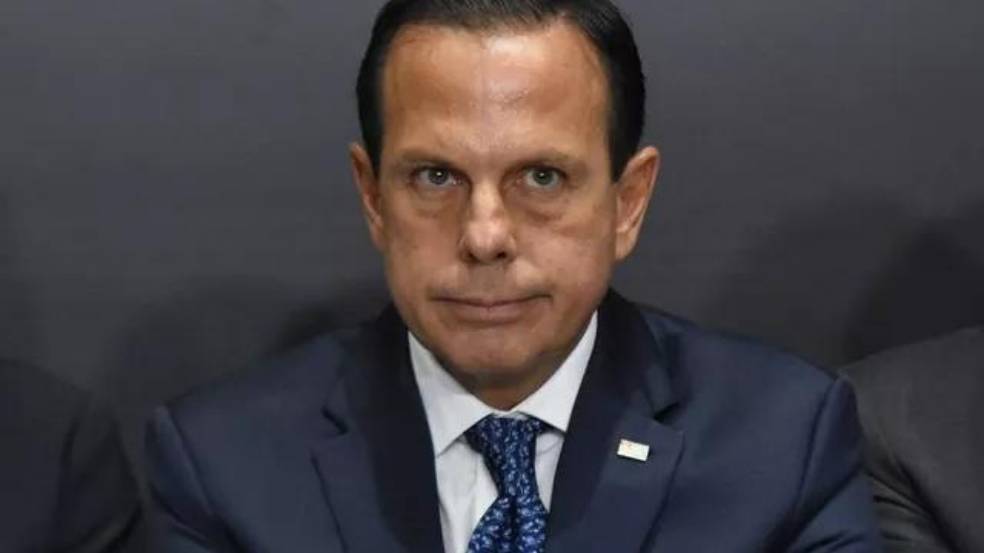 Bolsonaro é mal avaliado em pesquisa sobre desempenho na pandmeia. Doria tem olhar preocupado e sério, usa terno preto e cabelos pretos.