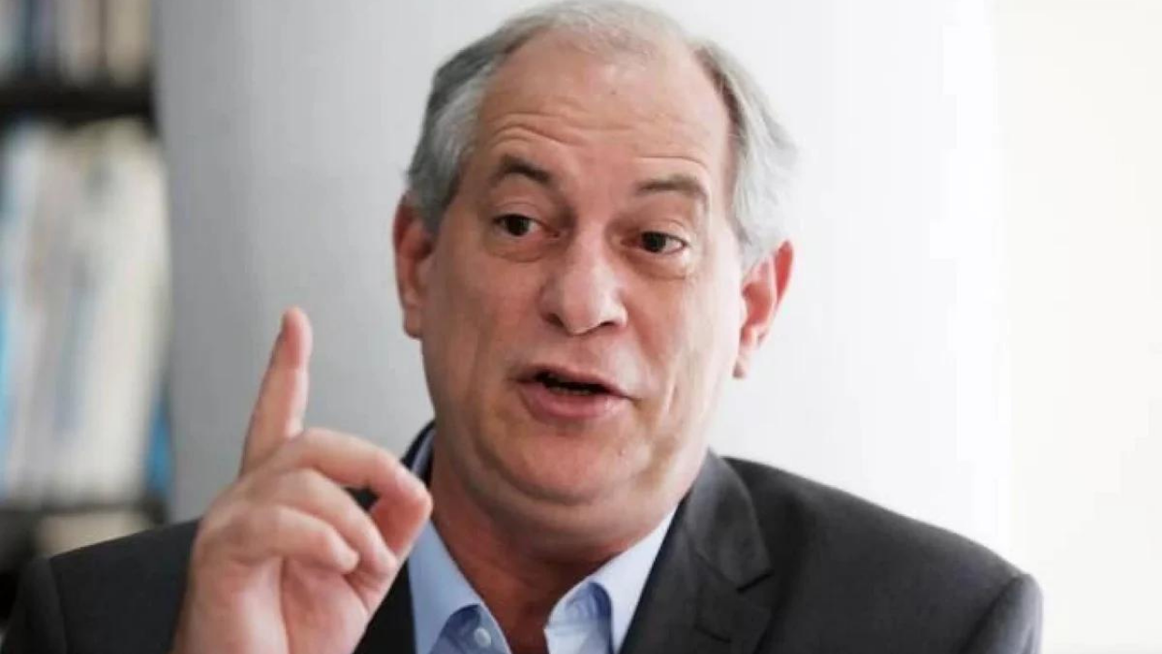 Ciro Gomes com o dedo indicador d amãe direita levantado, ele usa terno preto e tem cabelos brancos.