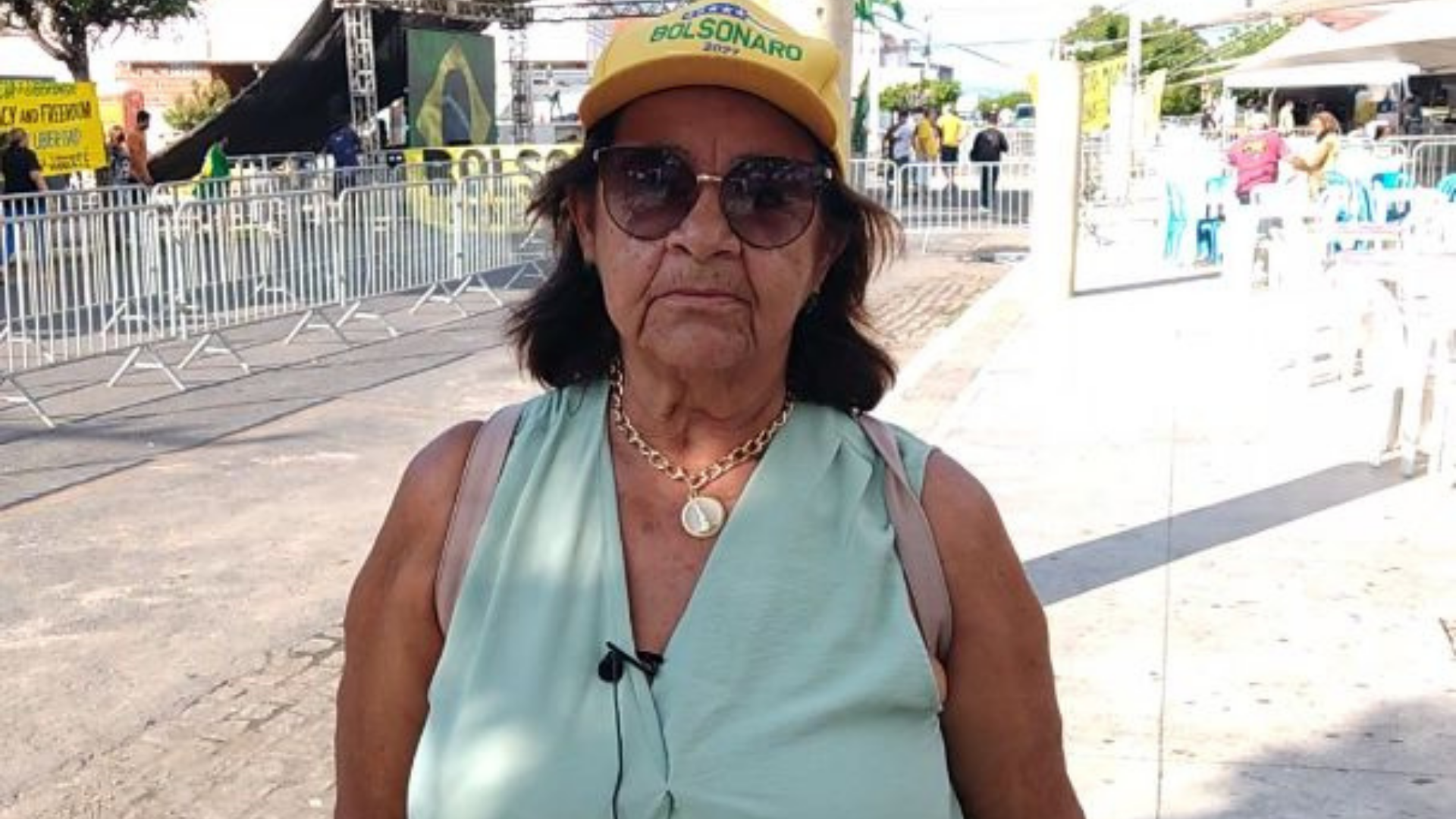 Raimunda Linhares usa blusa azul, tem pele negra, óculos de sol e boné verde e amarelo.