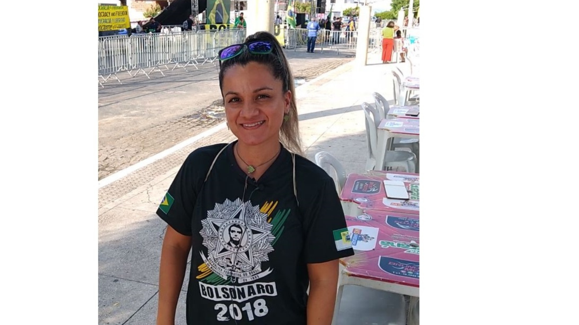 Ana Paula usa camisa escrita com o nome "Bolsonaro 2018". Ela está sorrindo e tem o cabelo preso em formato rabo de cavalo.