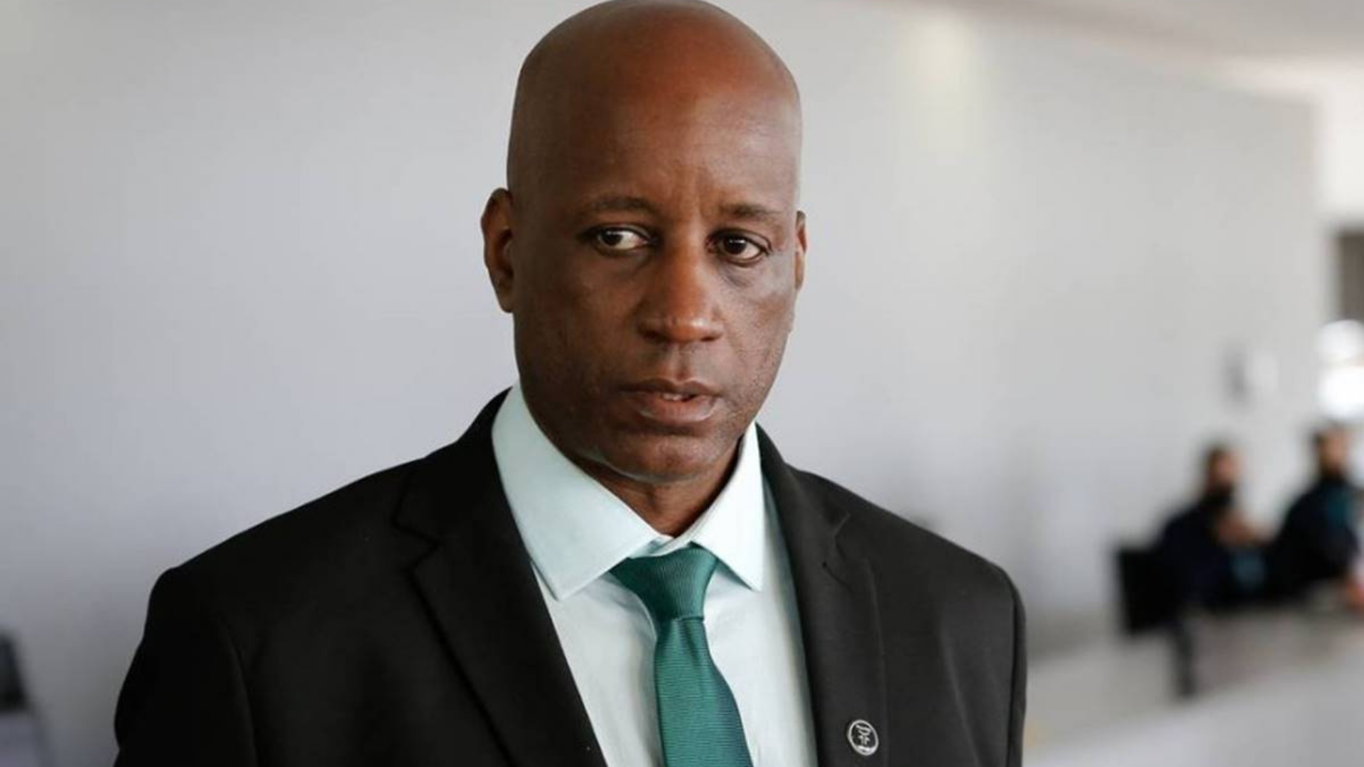 Sergio Camargo usa terno preto, é careca, negro e tem expressão de seriedade.