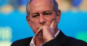 Foto de ciro Gomes com terno preto e olhar preocupado. Ele coloca a mão esquerda na bochecha