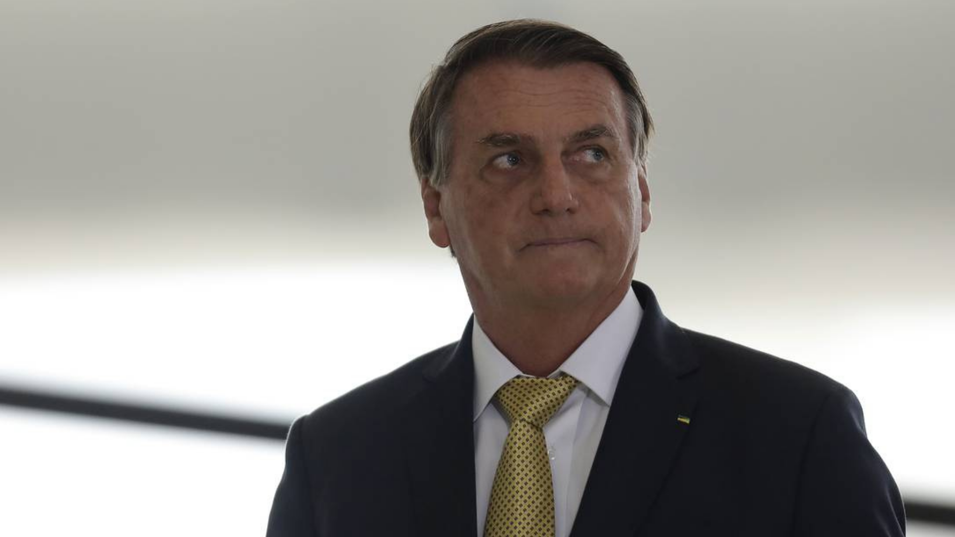 Bolsonaro vai à Rússia garantir entrega de fertilizante agrícola. Ele usa terno preto e tem olhar desconcertado.