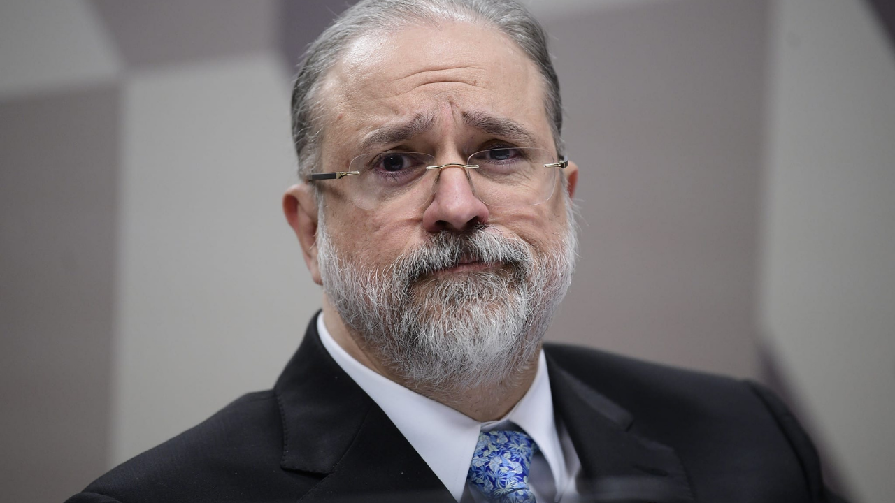 Augusto Aras diz que deu andamento em investigações. Ele usa terno preto, barba e cablo grisalhos, óculos de grau e pele branca