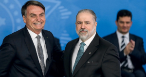 Foto deAgusto Aras, com terno preto, barba e cabelos brancos, e Bolsonaro, sorrindo, com cabelo castanho e terno preto.