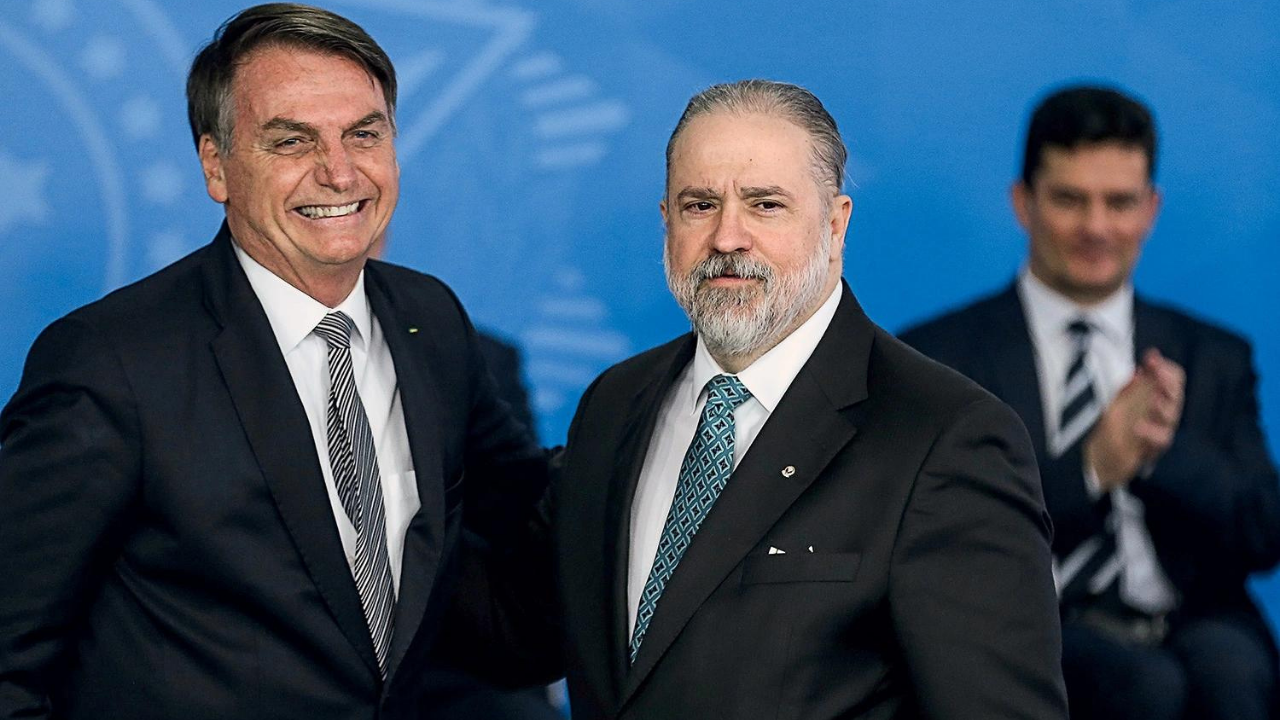Foto deAgusto Aras, com terno preto, barba e cabelos brancos, e Bolsonaro, sorrindo, com cabelo castanho e terno preto.