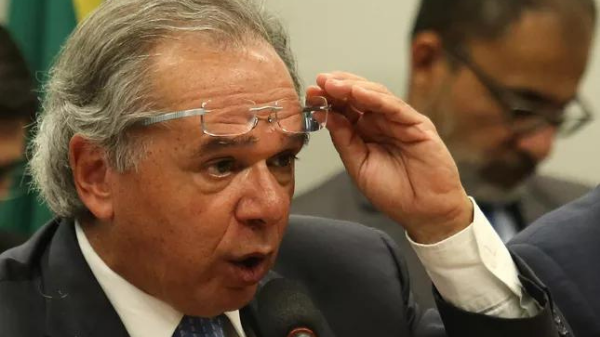 Paulo Guedes recebe carta de funcionários por reajuste. Ele tem o óculos levantado dos olhos e expressão de susto.