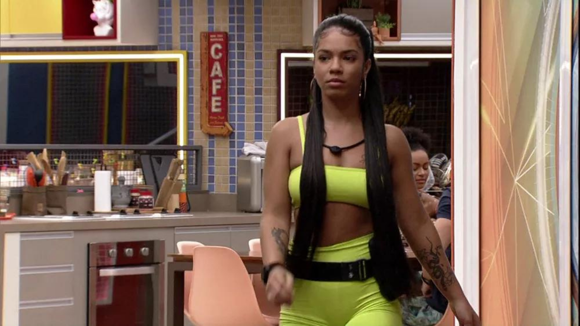 Maria expulsa do BBB 22. Ela usa macacão amarelo e cabelo preso, tem expressão séria e triste.