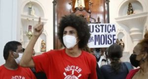 O vereador Renato Freitas (PT), de Curitiba, e os manifestantes, discursando dentro da igreja, com cartazes pedindo justiça para Moise e Durval.