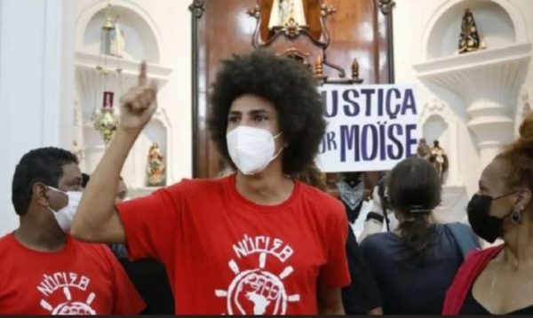 O vereador Renato Freitas (PT), de Curitiba, e os manifestantes, discursando dentro da igreja, com cartazes pedindo justiça para Moise e Durval.