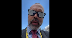Allan dos Santos afirma que Telegram não derrubou seu perfil. Ele usa terno cinza, gravata vermelha e óculos de sol.