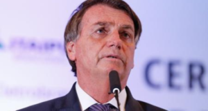 Rejeição de Bolsonaro dispara na web após Rússia invadir Ucrânia. Presidente aparece com expressão de preocupação e fala ao microfone eme evento. Fundo desfocado.