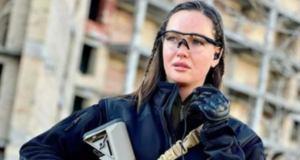 Com armas nas mãos, ex-miss Ucrânia incentiva população a ir à guerra. Ela usa equipamneto de proteção e segura um fuzil na mão.