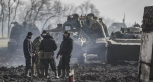 Agora vai: Guerra na Ucrânia pode ajudar 3ª via, diz o Valor. Foto de soldados em uma região atacada, ele estão na frente de um tanque de guerra.