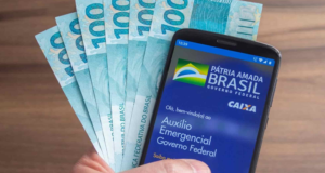Integrante da família Gracie é acusado de ter fraudado auxílio emergencial. Foto de celular aberto no aplicativo Caixa Tem e seis notas de 100 reais ao lado.