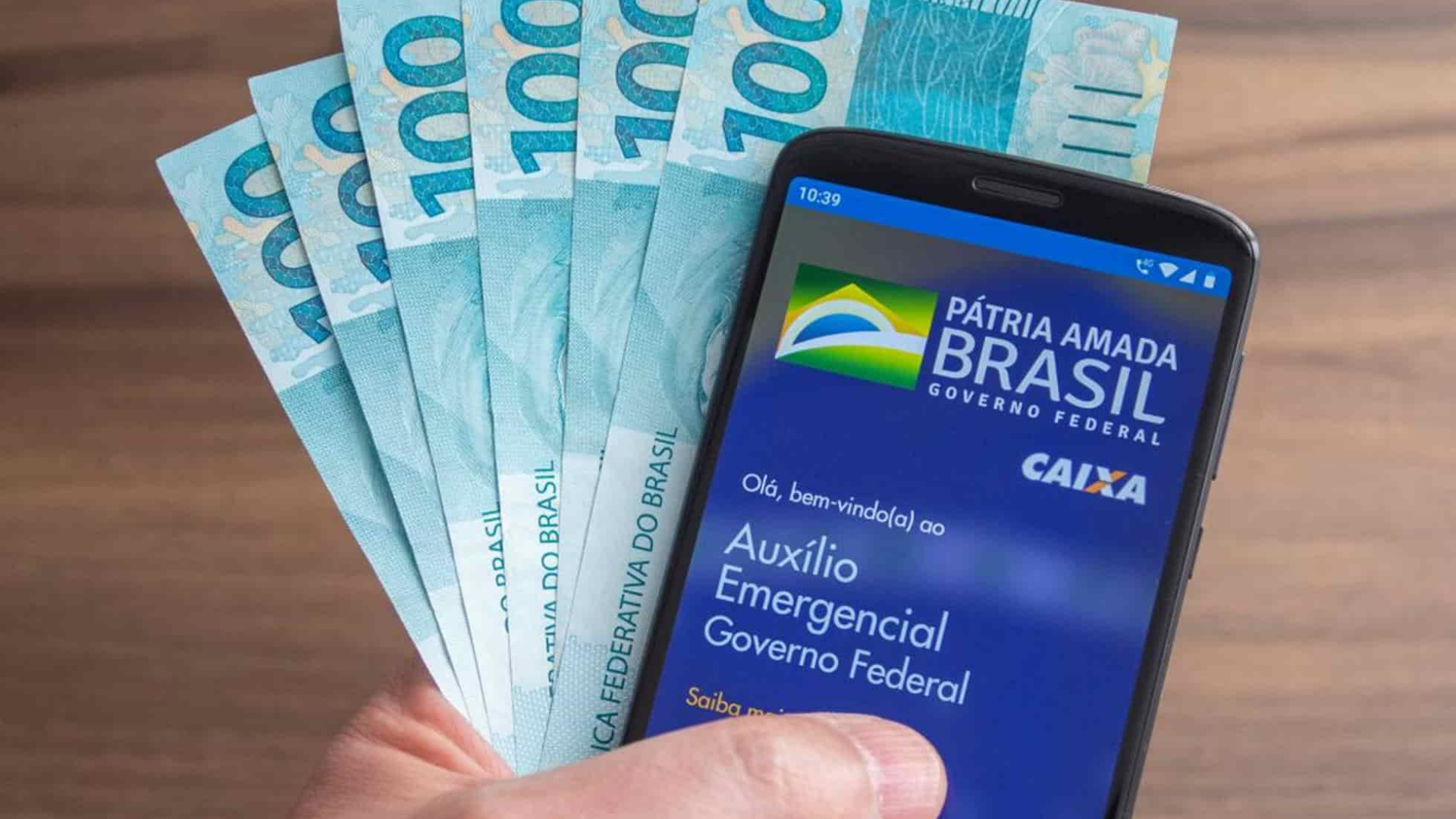 Integrante da família Gracie é acusado de ter fraudado auxílio emergencial. Foto de celular aberto no aplicativo Caixa Tem e seis notas de 100 reais ao lado.
