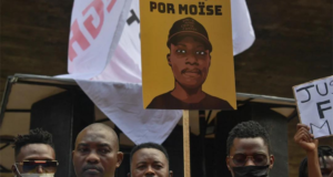 MPRJ denuncia suspeitos acusados de assassinar o congoles Moise. foto de manifestantes e um cartaz escrito "Justiça por Moïse"