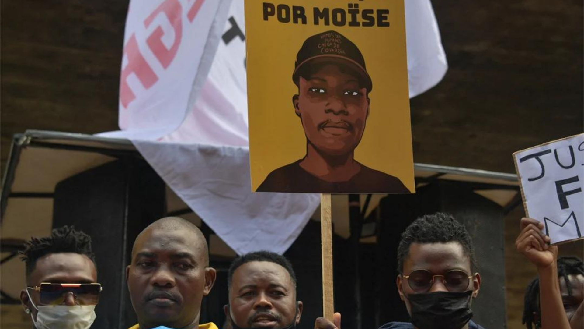 MPRJ denuncia suspeitos acusados de assassinar o congoles Moise. foto de manifestantes e um cartaz escrito "Justiça por Moïse"