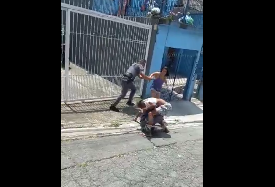 Trecho da abordagem da polícia, em que o homem está em luta corporal com um dos policiais. Outro PM chega para dar reforço. Uma mulher que manda os policias pararem com a violência também aparece na imagem.