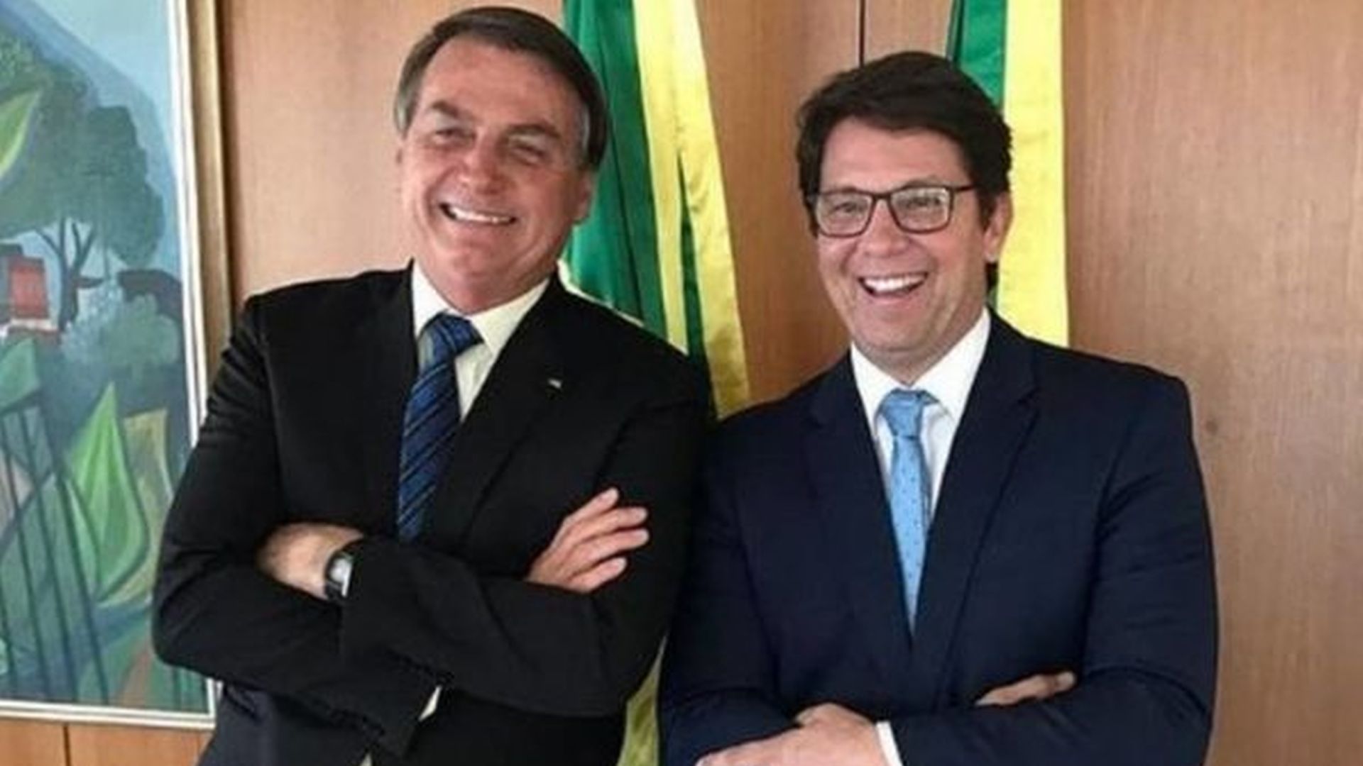Jair Bolsonaro e Mario Frias, em pé, um ao lado do outro, rindo
