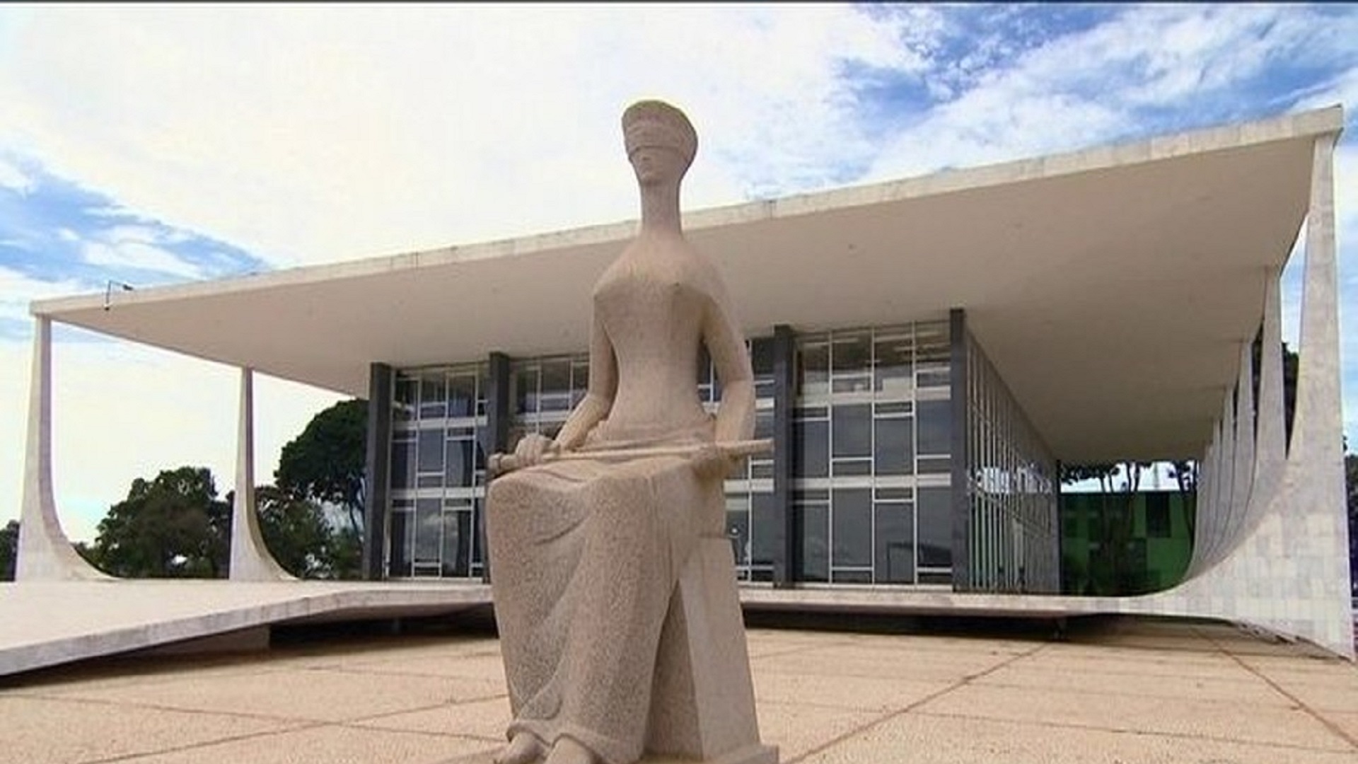 Imagem da frente do prédio do STF, com a estátua da justiça na frente.