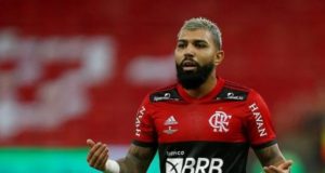 O jogador Gabi Gol é chamado de macaco durante jogo. Eçe usa camisa do Flamengo, usa barba e tem olhar sério.