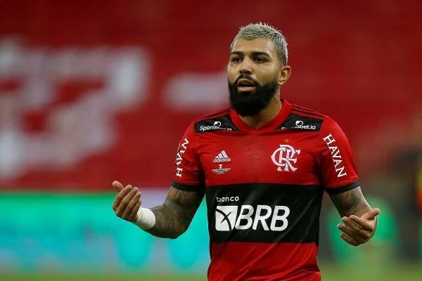 O jogador Gabi Gol é chamado de macaco durante jogo. Eçe usa camisa do Flamengo, usa barba e tem olhar sério.