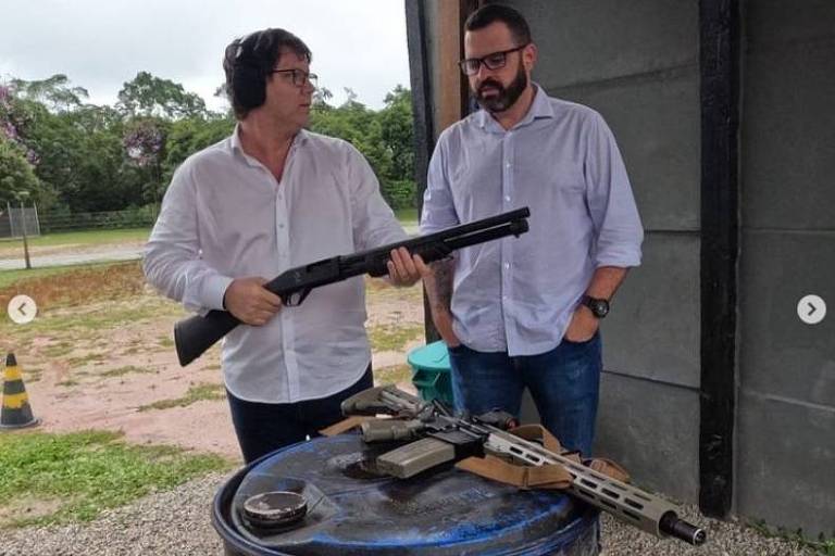 Mario Frias em um clube de tiro segurando uma arma escopeta. Ao seu lado, o vereador Paulo Chuchu, de São Bernardo do Campo.