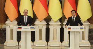 O líder da Alemanha, Olaf Scholz, e o presidente da Ucrânia, Zelensky, em encontro. Os dois estão lado a lado, cada um em um púlpito, para um discurso conjunto.