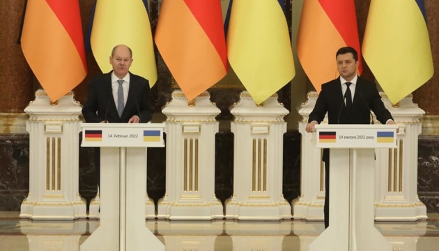 O líder da Alemanha, Olaf Scholz, e o presidente da Ucrânia, Zelensky, em encontro. Os dois estão lado a lado, cada um em um púlpito, para um discurso conjunto.