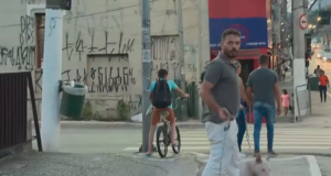 Homem acusado der ser o responsável pelas agressões segura um cachorro e a corrente que usou no ataque aos repórteres