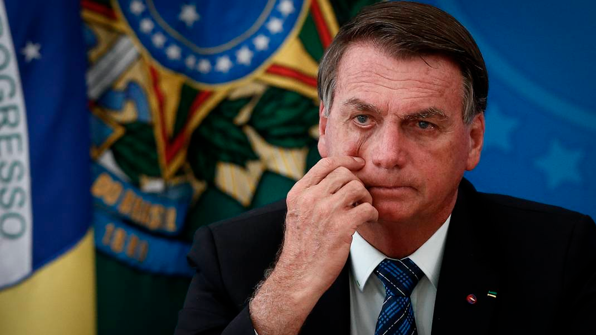 Presidente Bolsonaro passando a mão no rosto com olhar pensativo
