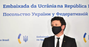 Diplomata da Ucrânia pede que Bolsonaro corte relações com a Rússia. Foto do diplomata com pele branca, usando máscara preta e óculos de grau. Ele também usa terno.