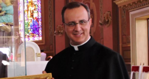 Papa Francisco expulsa padre acusado de abusos sexuais em SP. Padre sorri em foto usando roupa preta, sorrindo e com óculos de grau.