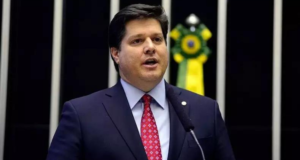 MDB bate martelo sofre federação partidária. Baleia Rossi discursa na Câmara com terno azul marinho.