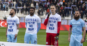Jogador se recusa a vestir camisa contra guerra na Ucrânia. Na foto, jogadores estão um ao lado do outro vestindo uma camisa contrária à guerra na Ucrânia, excete Aykut Demir, que veste a camisa do time.