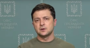 Zelensky diz que 'moderou' adesão à Otan. Presidente aparece gesticulando, com olhar firme, sem barba e usando uma camisa na cor marrom claro.