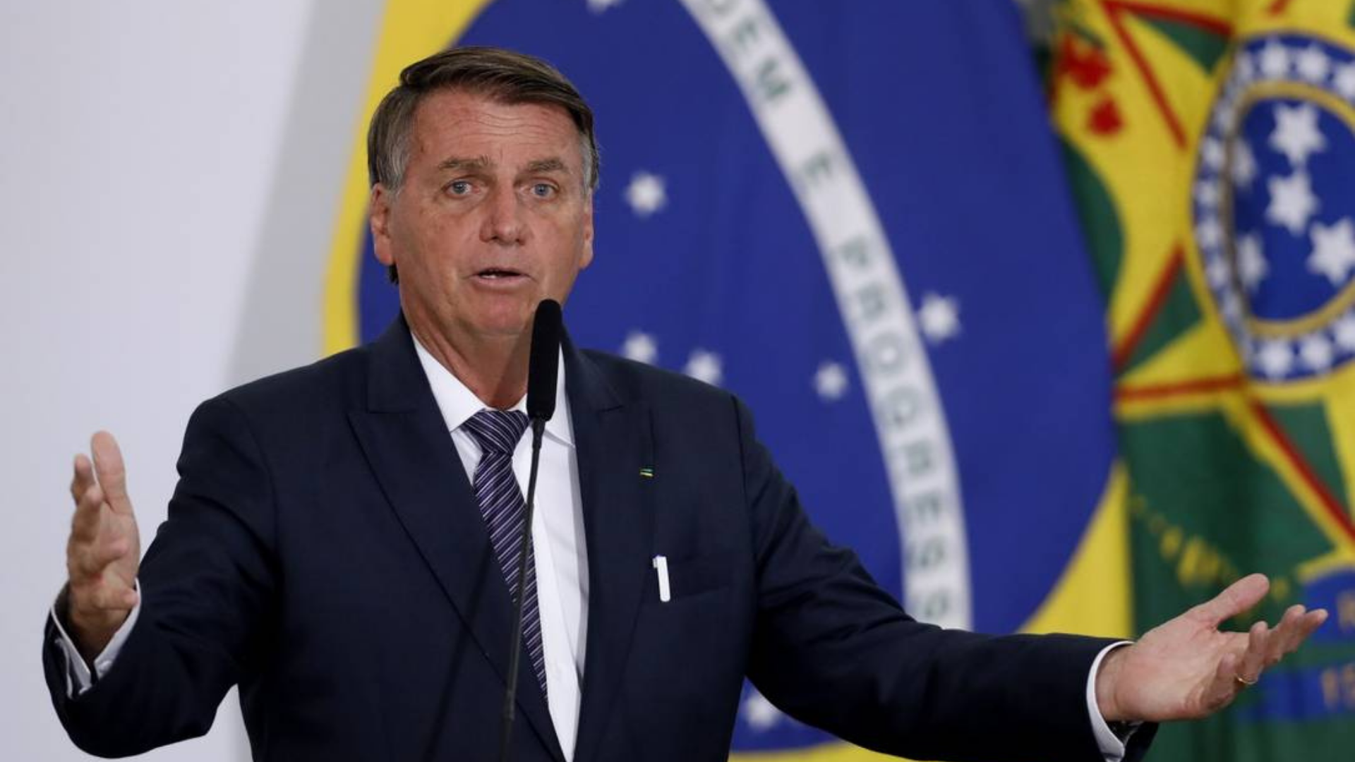 Datafolha: mais da metade do país não confia em Bolsonaro. Foto de Bolsonaro com olhar de dúvida e braços abertos.