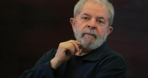 Inocente, Lula vai processar perseguidores. Foto de Lula usando terno preto com olhar sério.