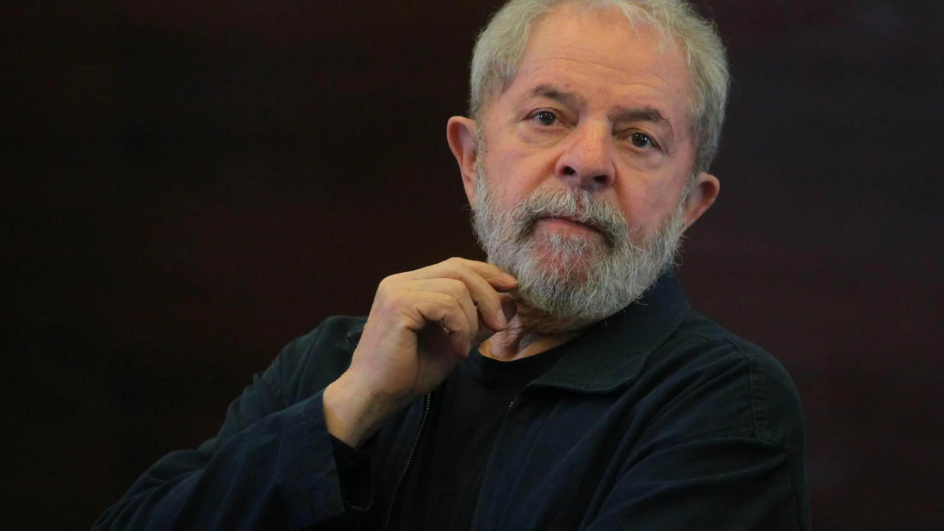 Inocente, Lula vai processar perseguidores. Foto de Lula usando terno preto com olhar sério.