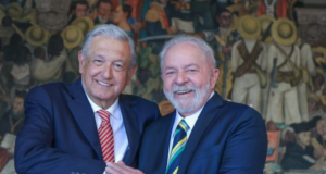 No México, ex-presidente Lula se reúne com López Obrador. Os dois aparecem sorrindo na foto, usando terno e com pele branca. Ambos também possuem cabelo grisalho.