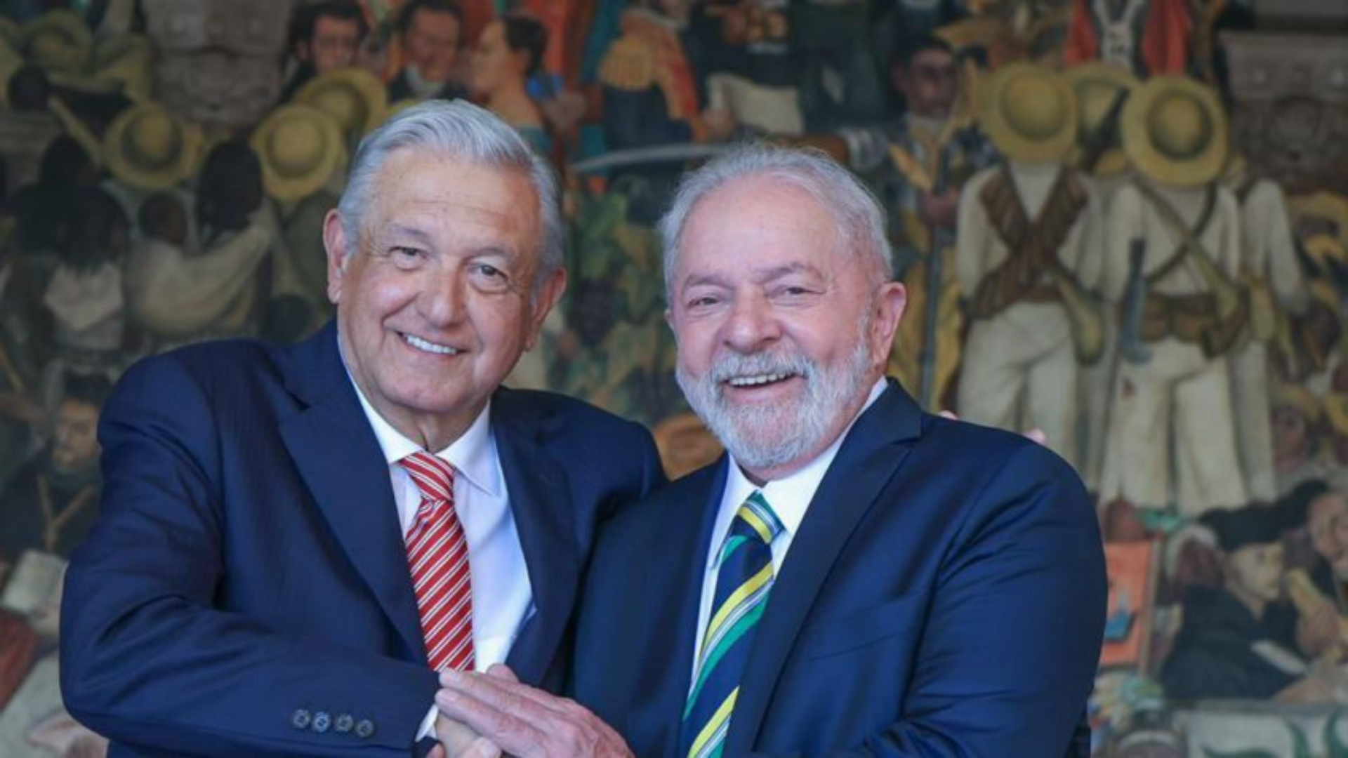 No México, ex-presidente Lula se reúne com López Obrador. Os dois aparecem sorrindo na foto, usando terno e com pele branca. Ambos também possuem cabelo grisalho.