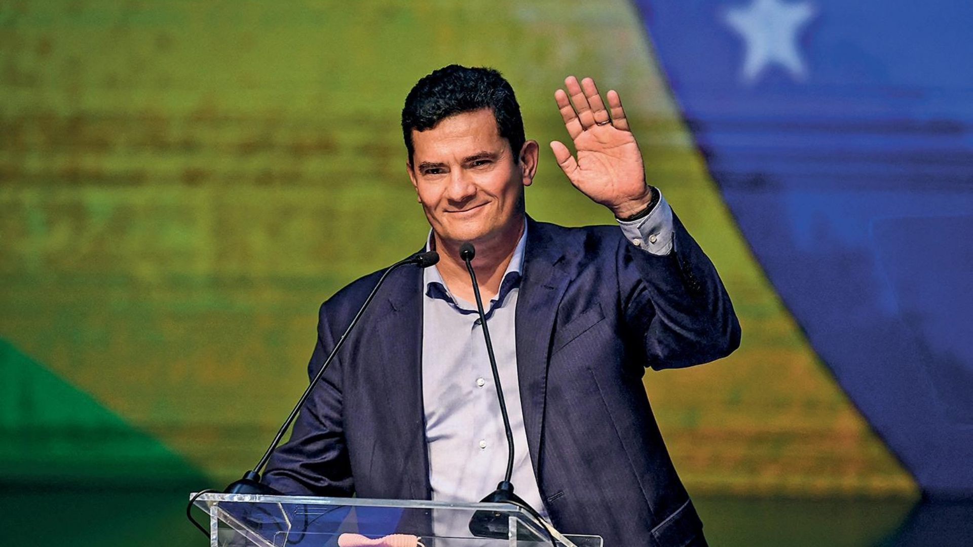 Podemos acusa Moro de “traição” após filiação ao União Brasil. Foto de Moro acenando e sorrindo.