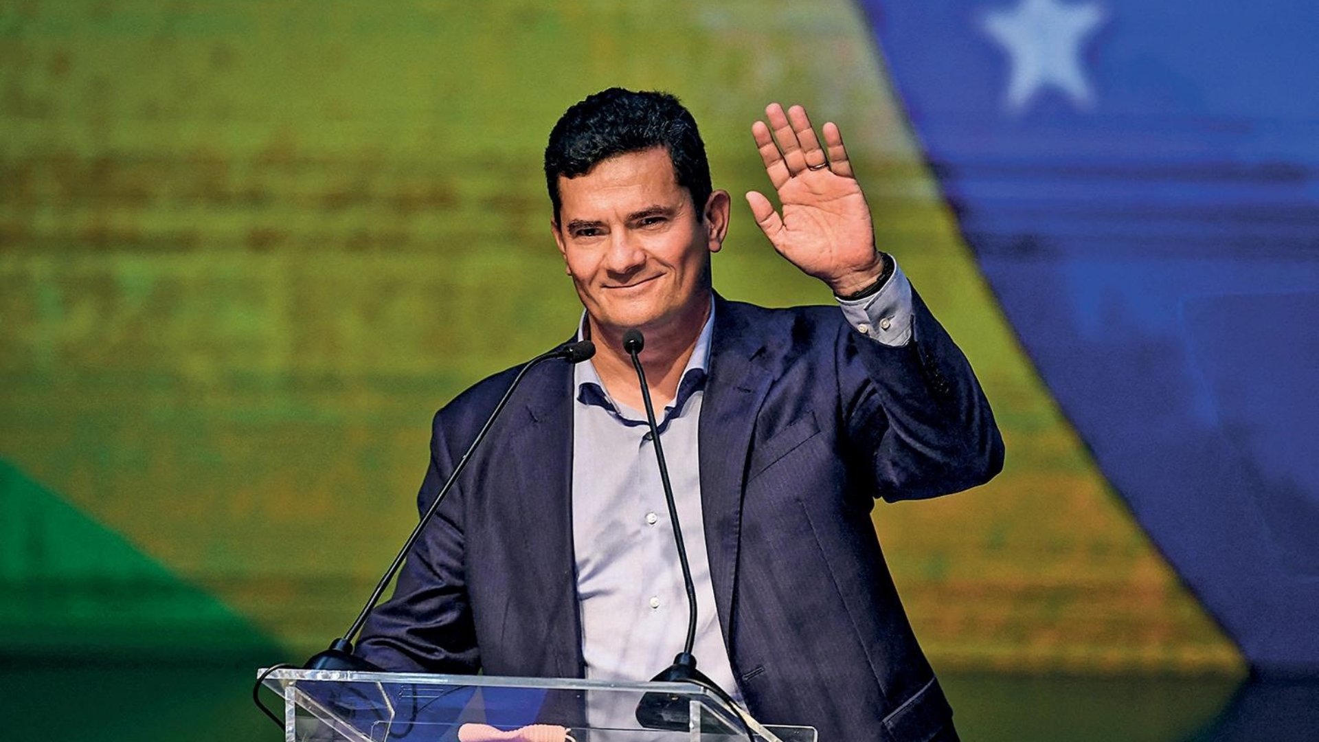 Podemos acusa Moro de “traição” após filiação ao União Brasil. Foto de Moro acenando e sorrindo. 