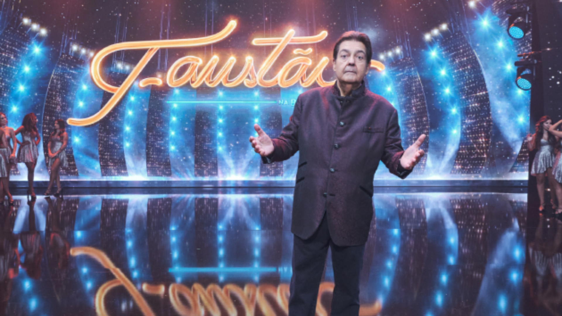 Funcionários do programa de Faustão reclamam de excesso de trabalho. Foto de faustão usando terno dentro do estúdio do programana na Band.